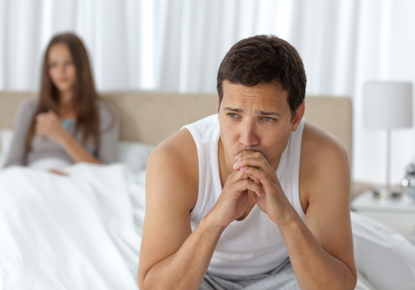Pensive man having a headache sitting on the bed
