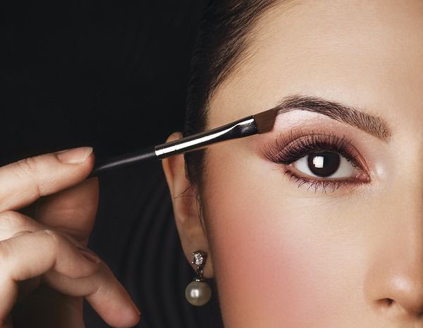 Elegant woman applying makeup on her eye